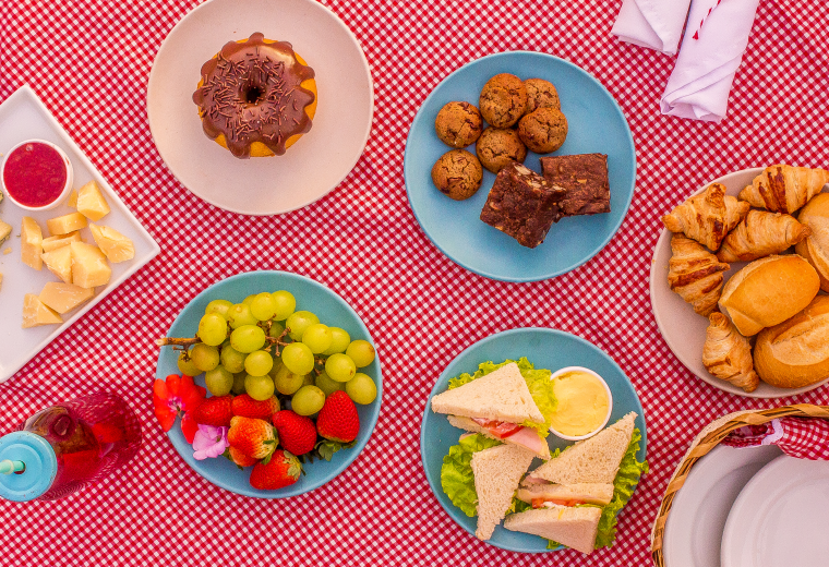 Picnic com bolos, cookies, croissant, frutas, sanduiches, pães